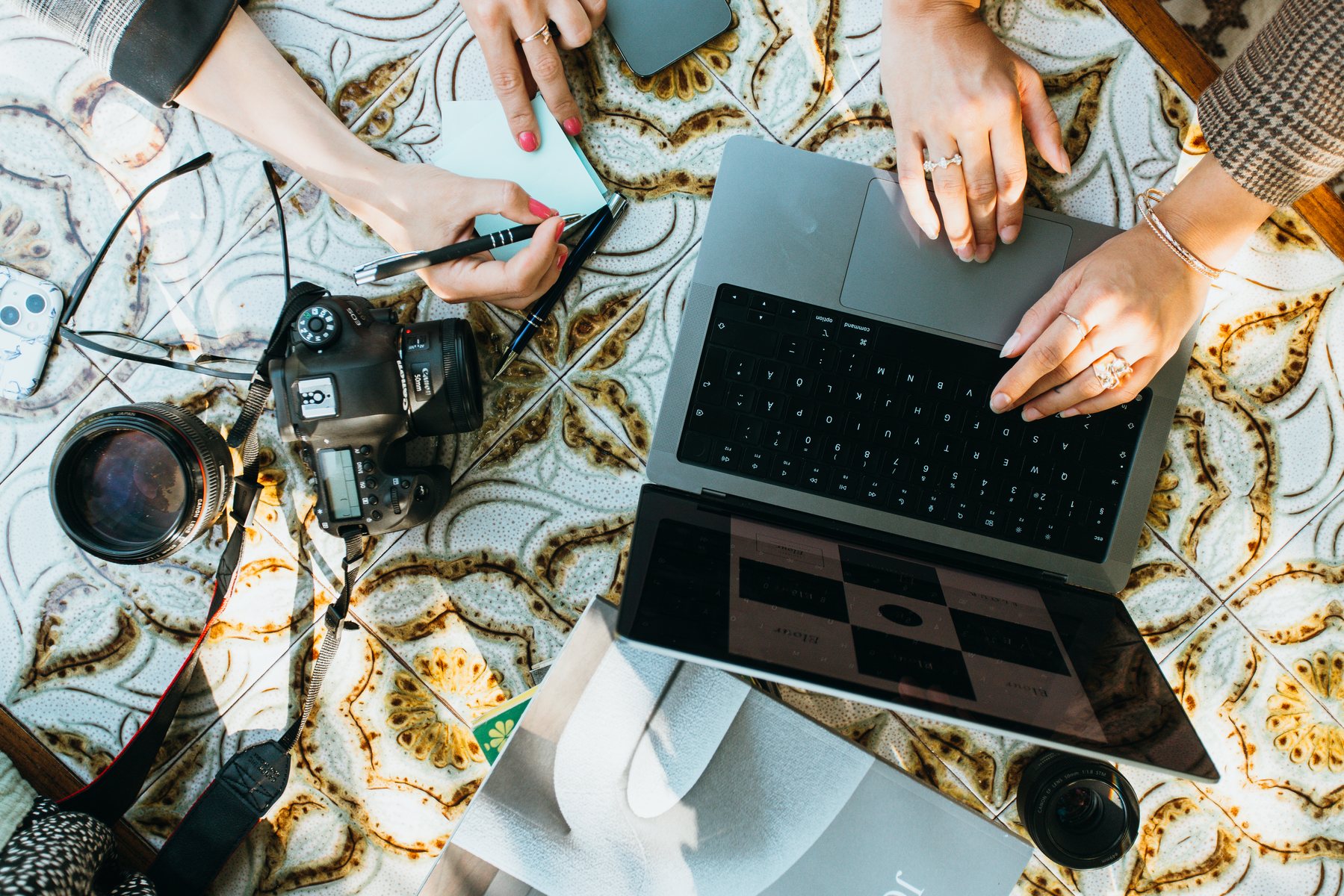 Camera, lens and laptop on a patterned table — Elour Creative at work